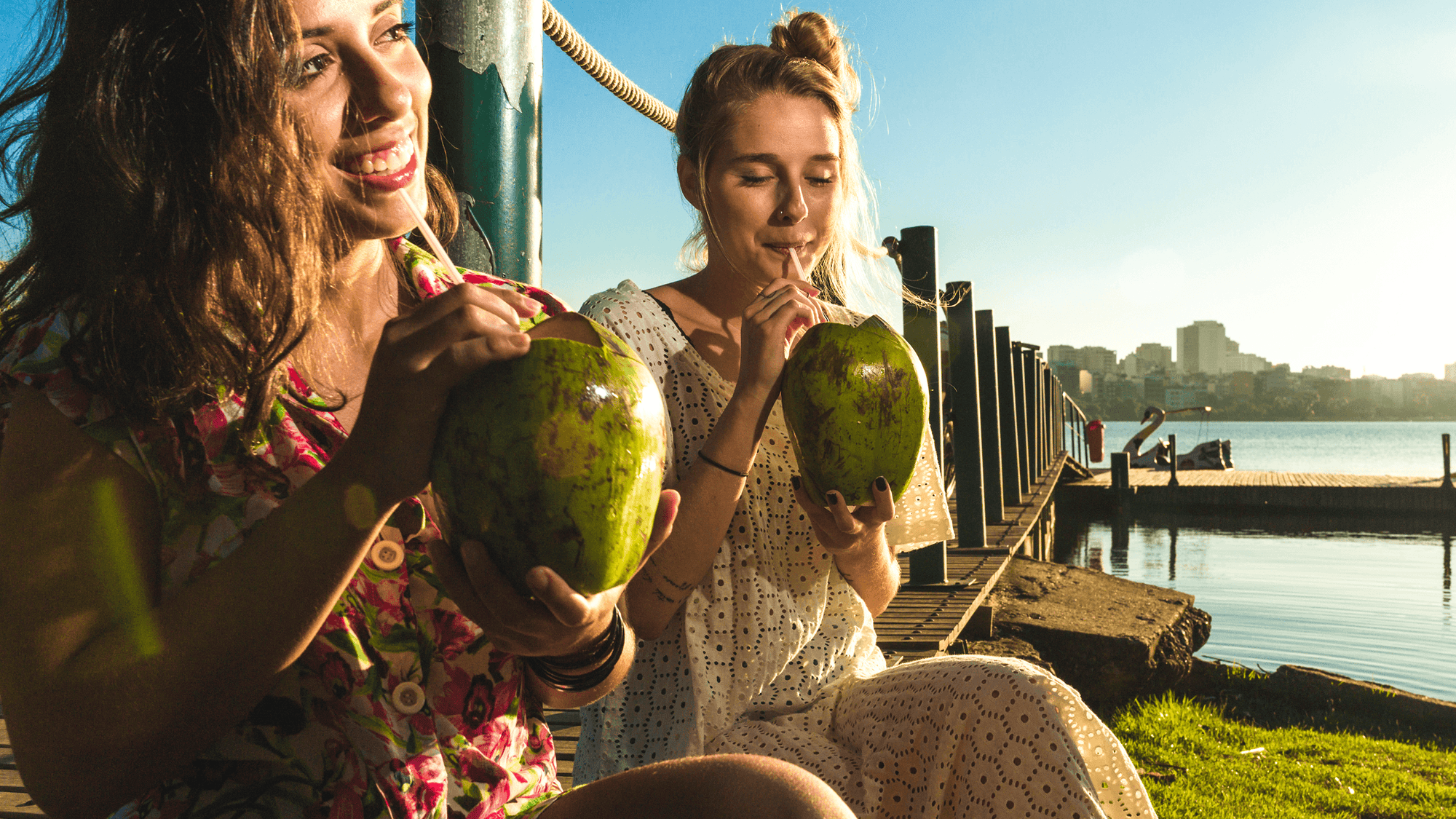 Two women drinking coconut water straight from the coconut